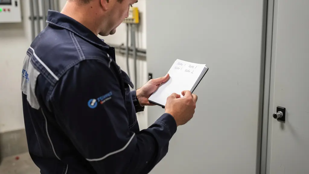 Technicien électricien consultant un carnet de prescriptions sur site industriel